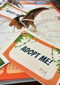 Toy Dinosaur with Adopt Me tag on a desktop calendar