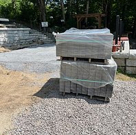Two pallets of pavers are on a gravel surface waiting to be placed in the patio area