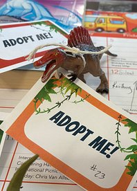 Toy Dinosaur with Adopt Me tag on a desktop calendar