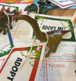 Toy Dinosaur with Adopt Me tag on a desktop calendar