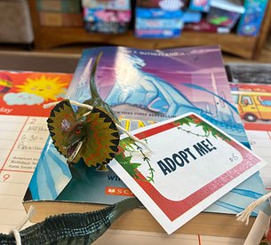 Toy Dinosaur with Adopt Me tag on a desktop calendar